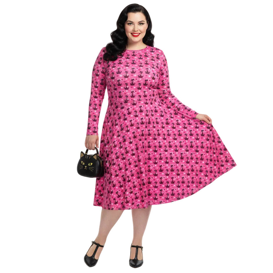 Plus size woman wearing a pink retro-style long sleeve vintage 1950s dress with cat print and functional side pockets.