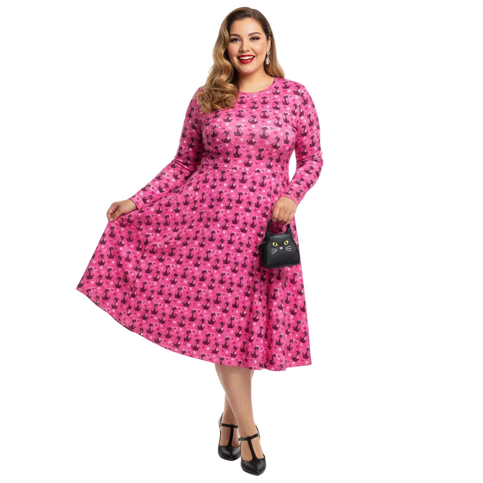 Plus size woman wearing a pink long sleeve vintage 1950s dress with cat print and functional side pockets.