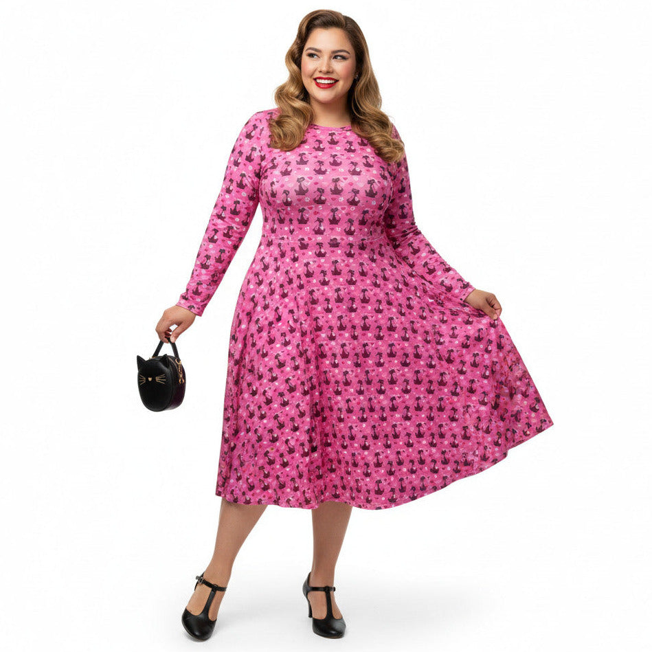 Plus size woman wearing a pink long sleeve vintage 1950s dress with cat print and functional side pockets.