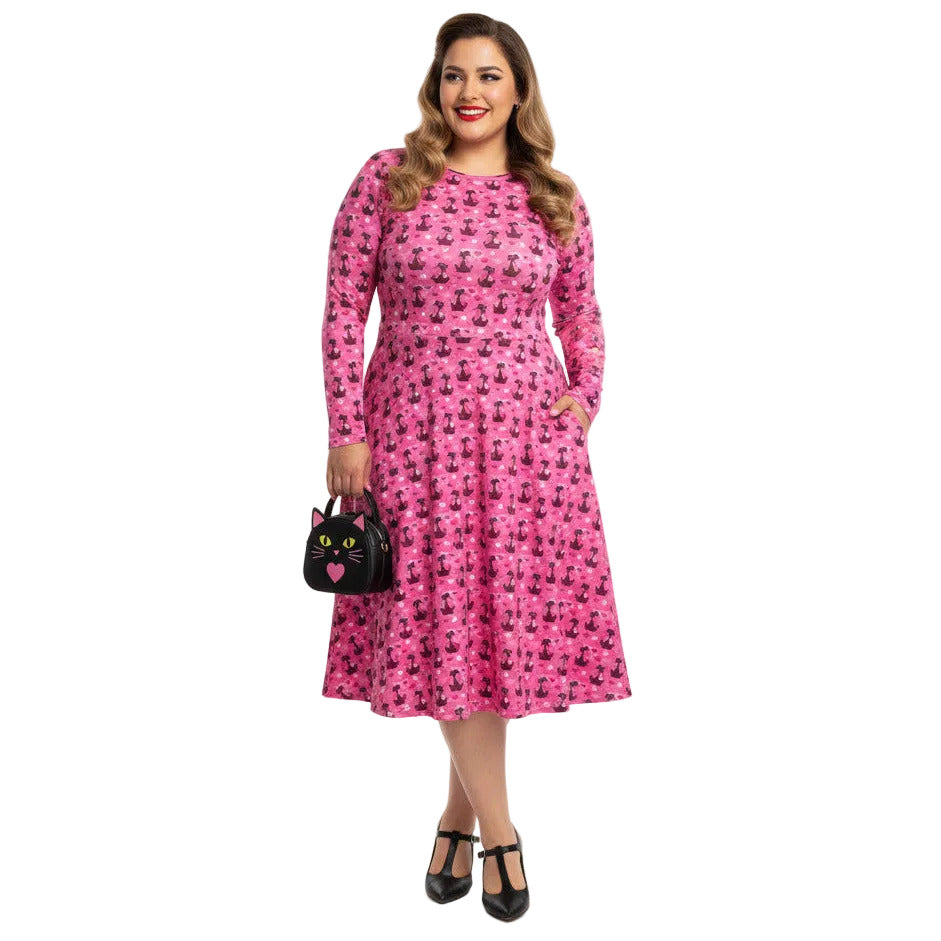 Plus size woman wearing a pink long sleeve vintage 1950s dress with cat print and functional side pockets.