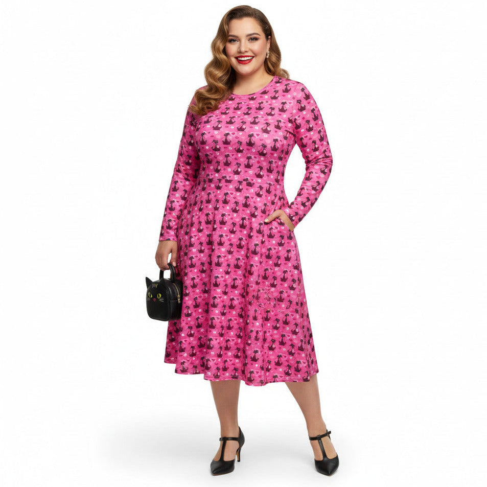 Plus size woman wearing a pink long sleeve vintage 1950s dress with cat print and functional side pockets.