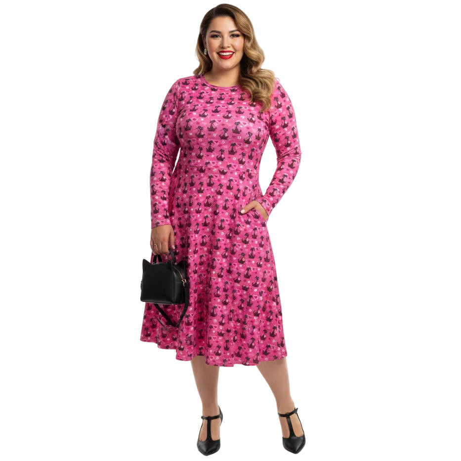 Plus size woman wearing a pink long sleeve vintage 1950s dress with cat print and functional side pockets.