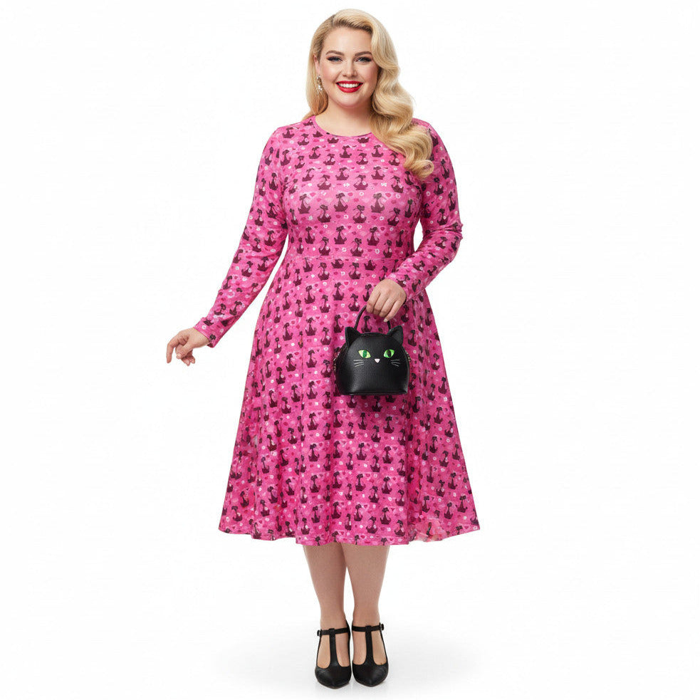 Woman wearing a pink long sleeve vintage-inspired 1950s dress with cat print and functional side pockets.