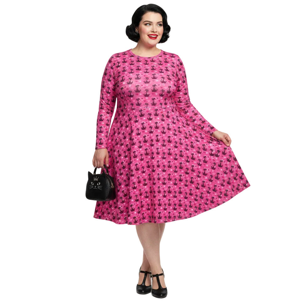 Woman wearing a pink long sleeve vintage-inspired 1950s dress with cat print and functional side pockets.