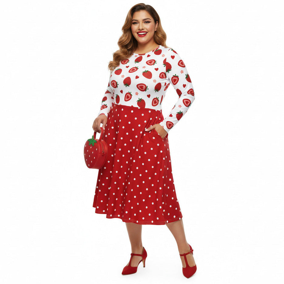 Plus size woman wearing a long sleeve white and red strawberry pin-up swing dress with red polka dot skirt and pockets.