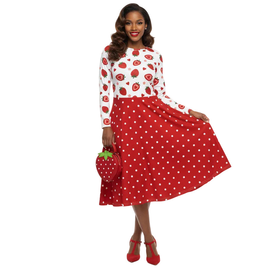 woman wearing a long sleeve white and red strawberry pin-up swing dress with red polka dot skirt and pockets.