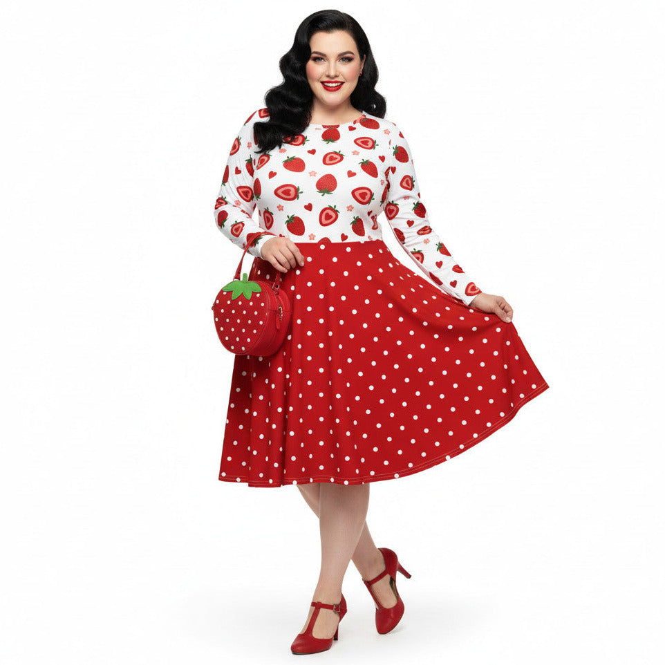 Plus size woman wearing a long sleeve white and red strawberry pin-up swing dress with red polka dot skirt and pockets.