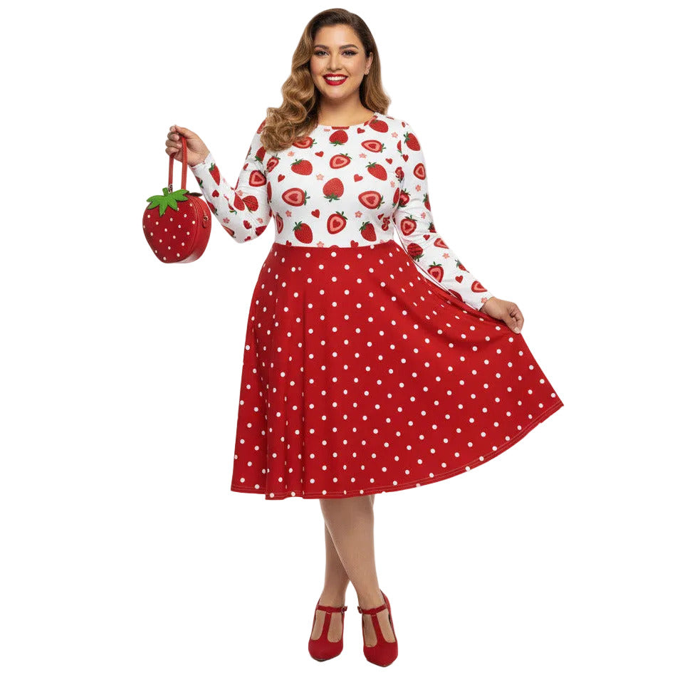 Plus size woman wearing a long sleeve white and red strawberry pin-up swing dress with red polka dot skirt and pockets.