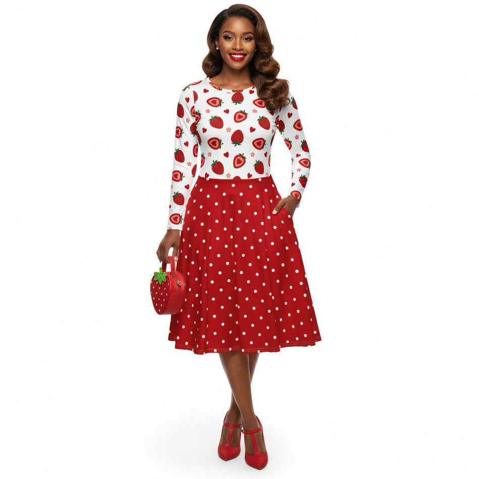 woman wearing a long sleeve white and red strawberry pin-up swing dress with red polka dot skirt and pockets.