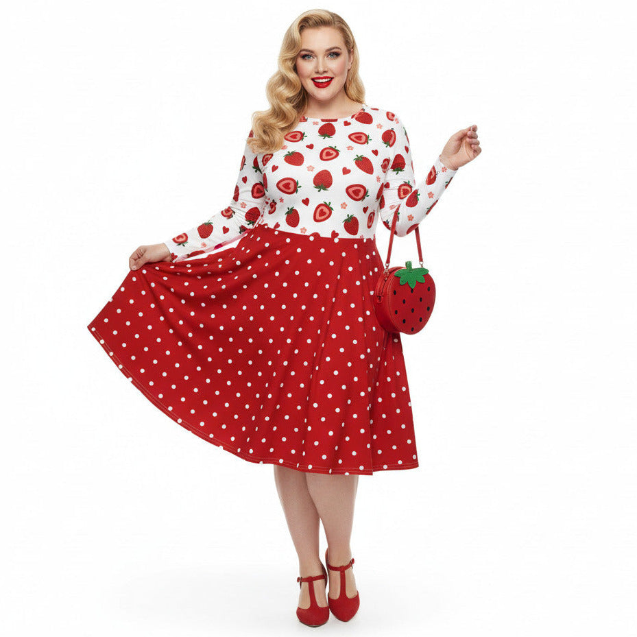 Plus size woman wearing a long sleeve white and red strawberry pin-up swing dress with red polka dot skirt and pockets.