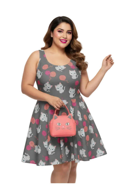 Woman wearing a plus size grey 1950s vintage swing dress with white cat and pink yarn print, holding a pink cat-shaped handbag.