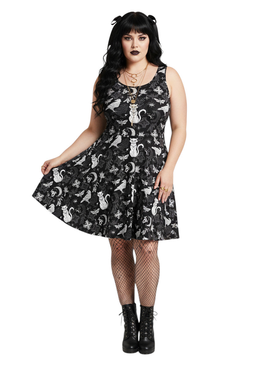 Woman wearing a Whimsigoth fit and flare dress with witchy cat and celestial moon prints.