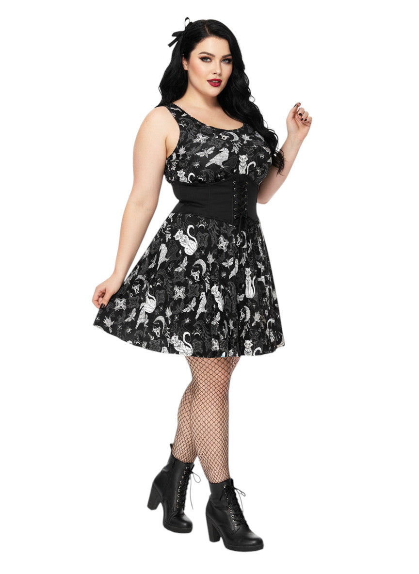 Woman wearing a Whimsigoth fit and flare dress with witchy cat and celestial moon prints.
