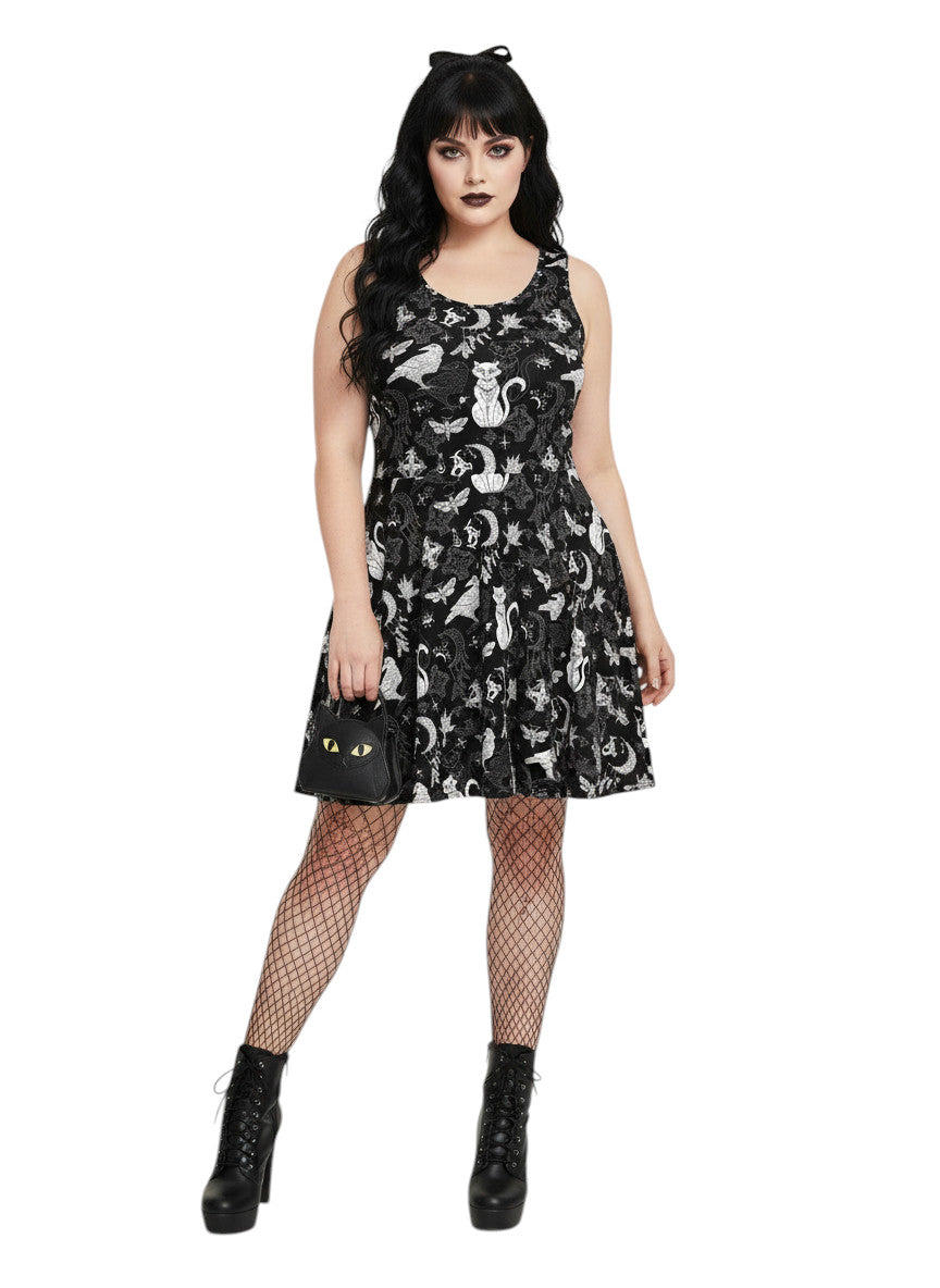 Woman wearing a Whimsigoth fit and flare dress with witchy cat and celestial moon prints.