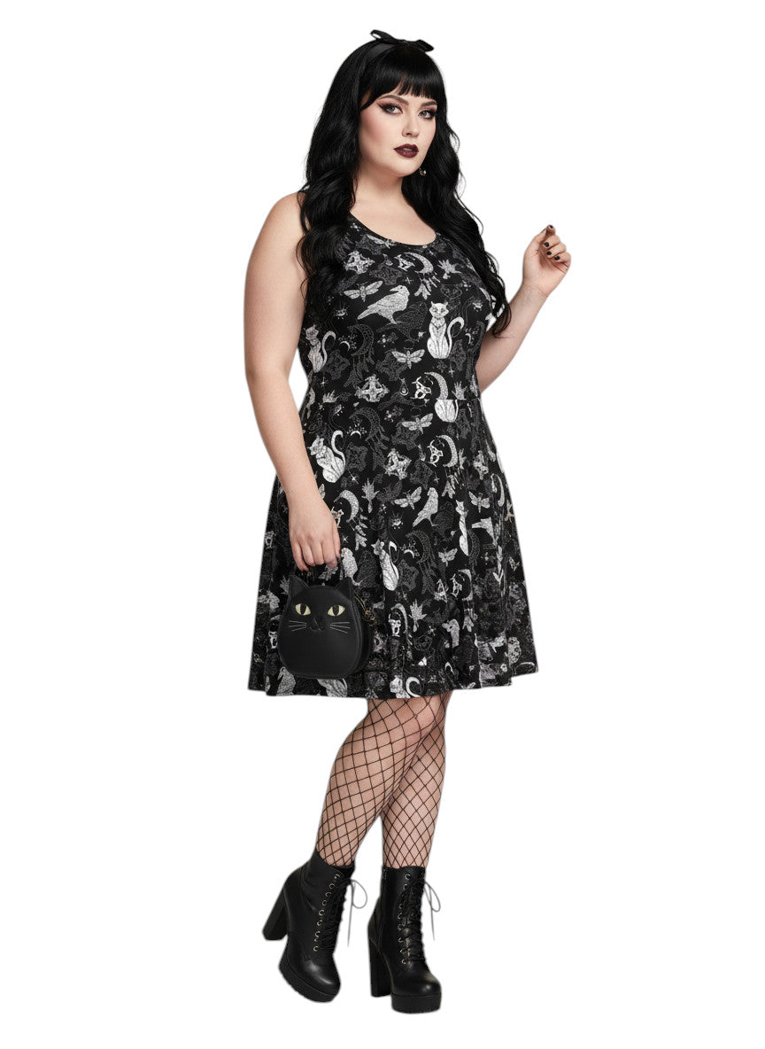 Woman wearing a Whimsigoth fit and flare dress with witchy cat and celestial moon prints.