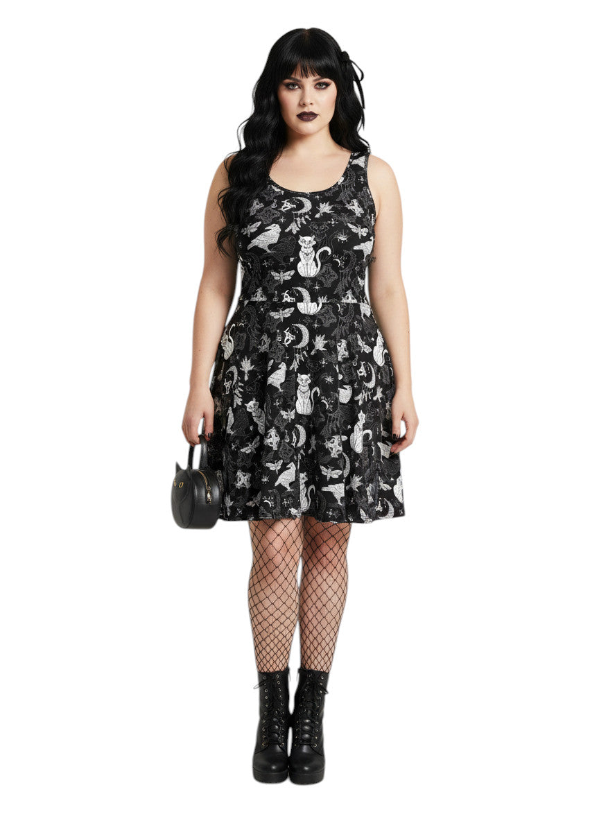 Woman wearing a Whimsigoth fit and flare dress with witchy cat and celestial moon prints.