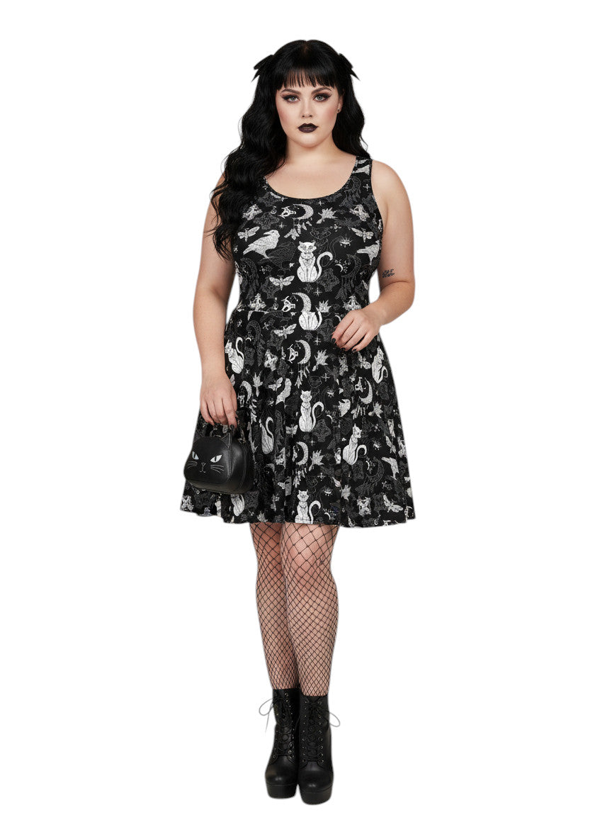 Woman wearing a Whimsigoth fit and flare dress with witchy cat and celestial moon prints.
