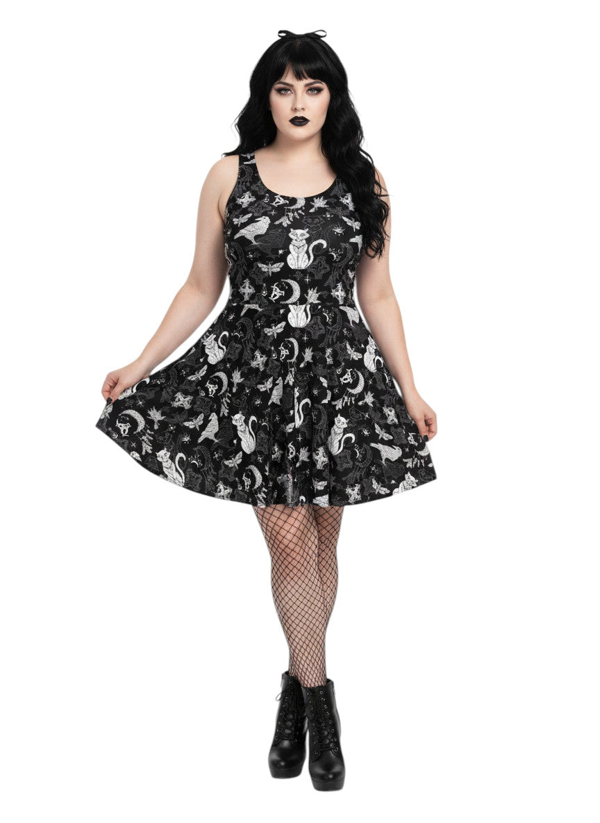 Woman wearing a Whimsigoth fit and flare dress with witchy cat and celestial moon prints.