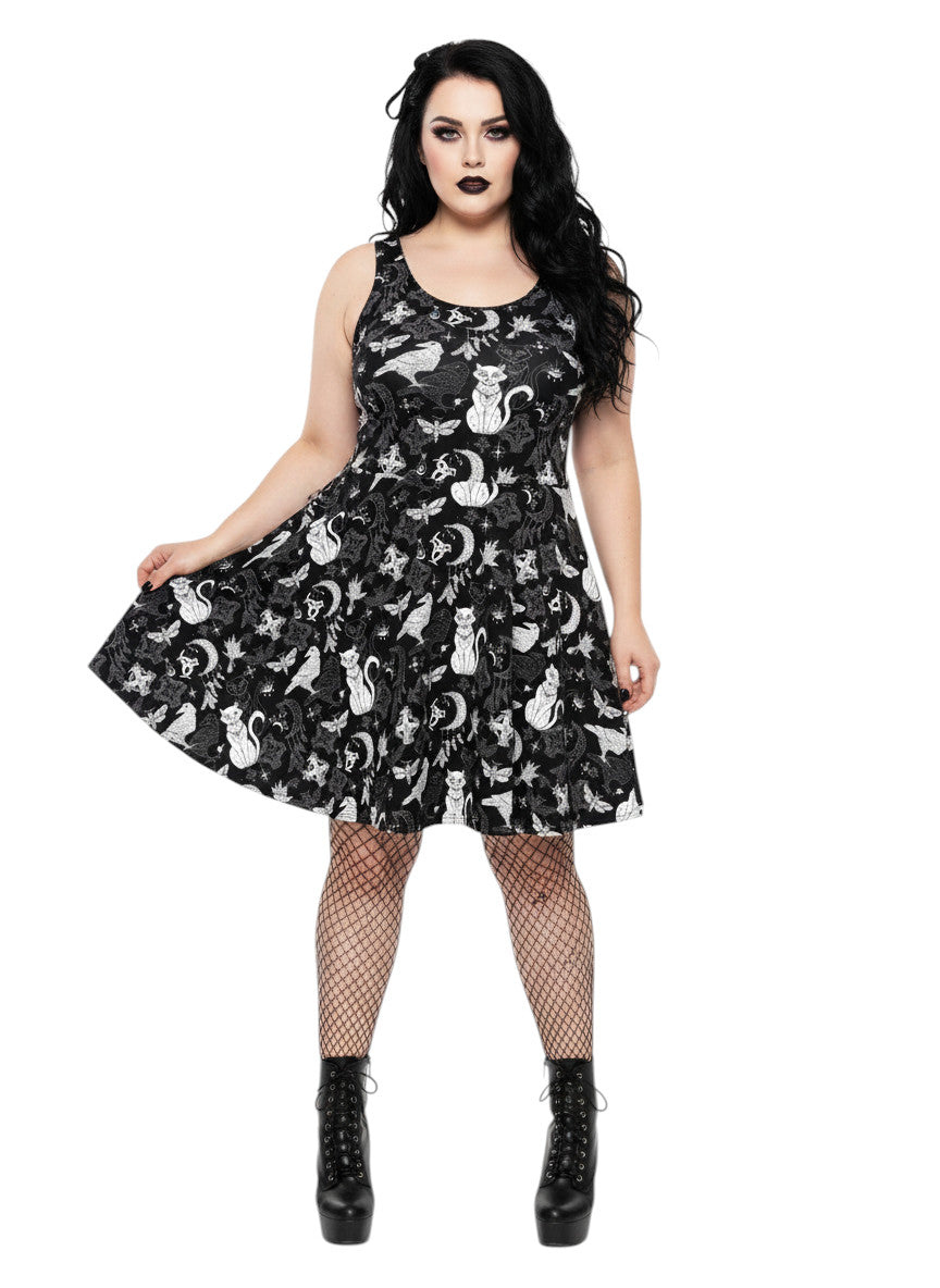 Woman wearing a Whimsigoth fit and flare dress with witchy cat and celestial moon prints.