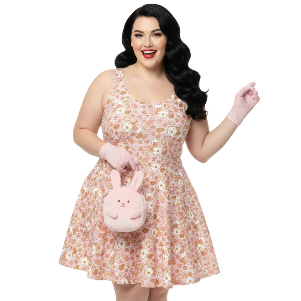 Plus size woman wearing a 1950s style pink Easter bunny print swing dress with a fit and flare silhouette.