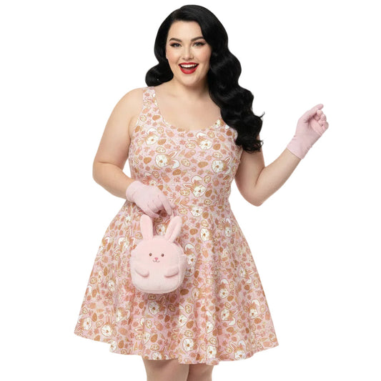 Plus size woman wearing a 1950s style pink Easter bunny print swing dress with a fit and flare silhouette.