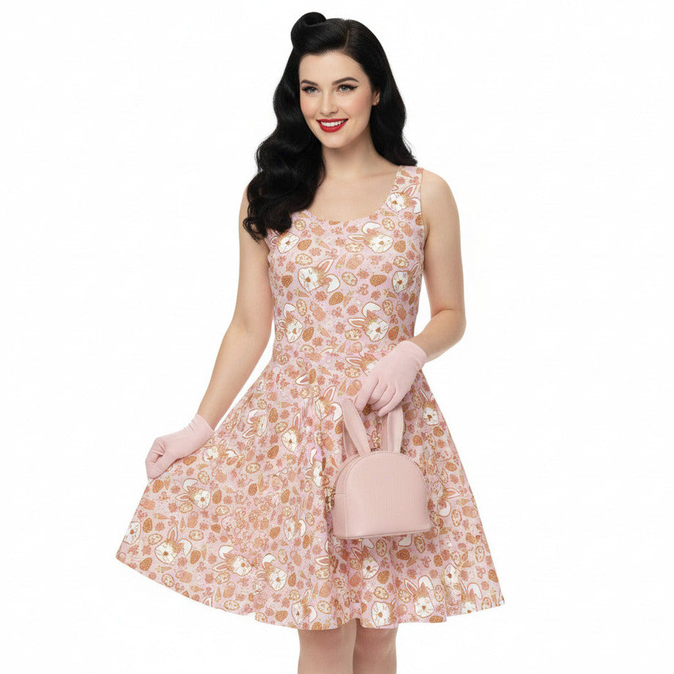Woman wearing a 1950s style pink Easter bunny print swing dress with a fit and flare silhouette.