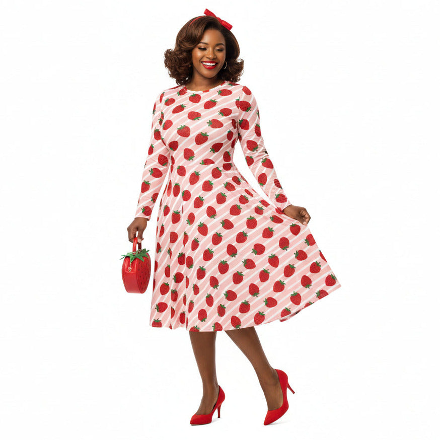 Woman wearing pink and red strawberry print longsleeve dress with pockets on white background