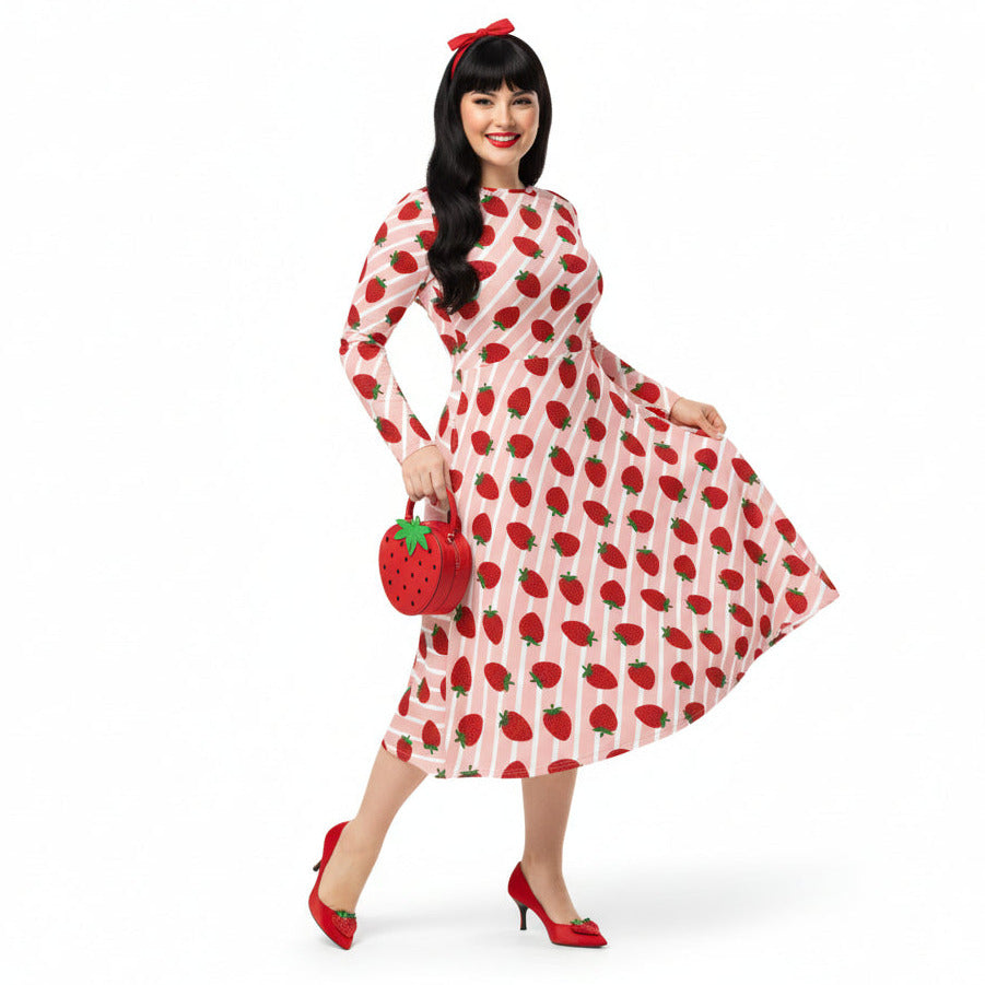 Woman wearing pink and red strawberry print longsleeve dress with pockets on white background