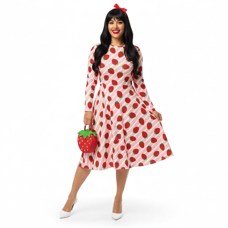 Woman wearing pink and red strawberry print longsleeve dress with pockets on white background