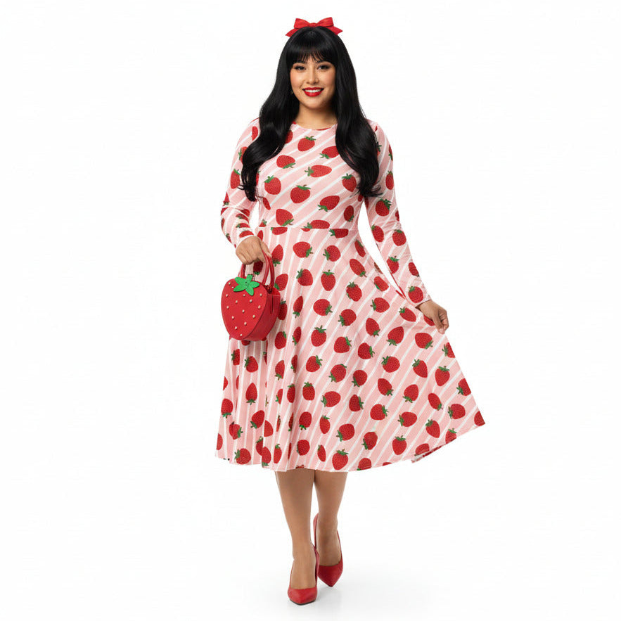 Woman wearing pink and red strawberry print longsleeve dress with pockets on white background