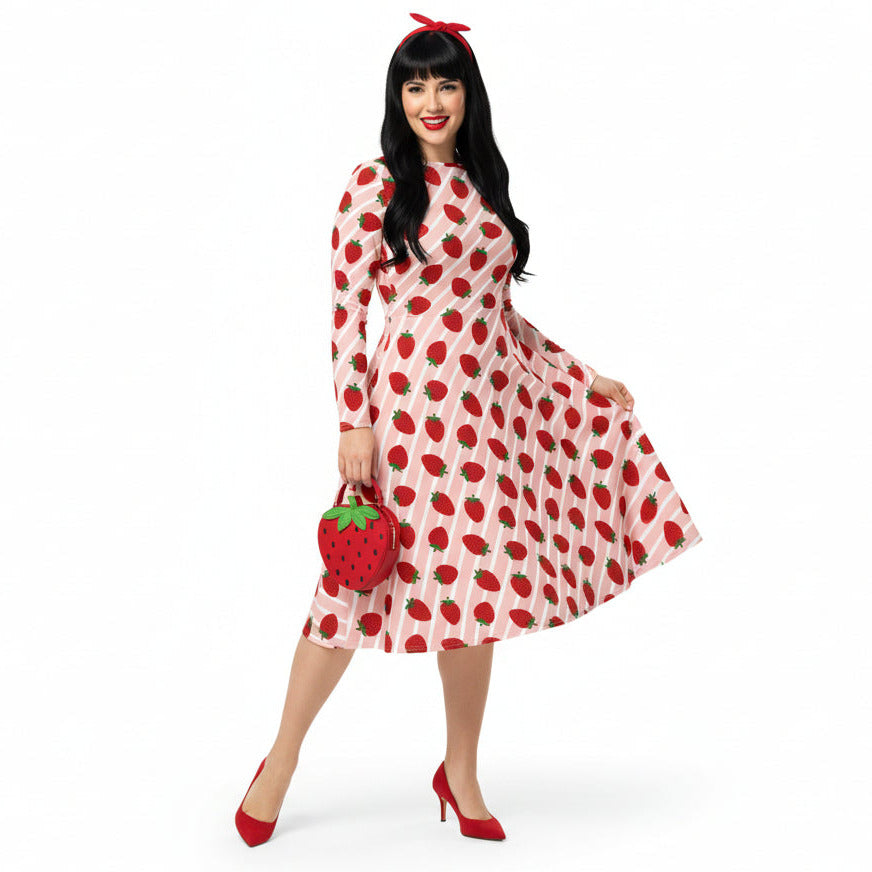 Woman wearing pink and red strawberry print longsleeve dress with pockets on white background