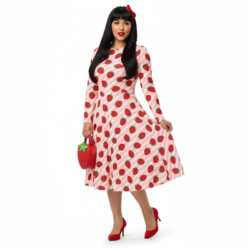 Woman wearing pink and red strawberry print longsleeve dress with pockets on white background