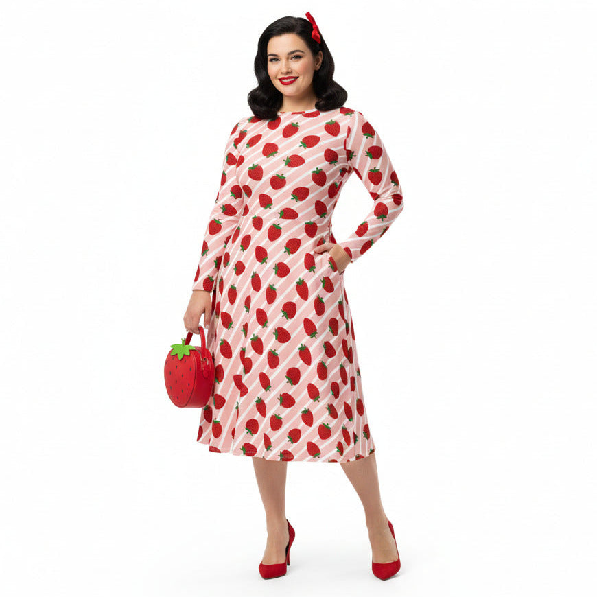 Woman wearing pink and red strawberry print longsleeve dress with pockets on white background