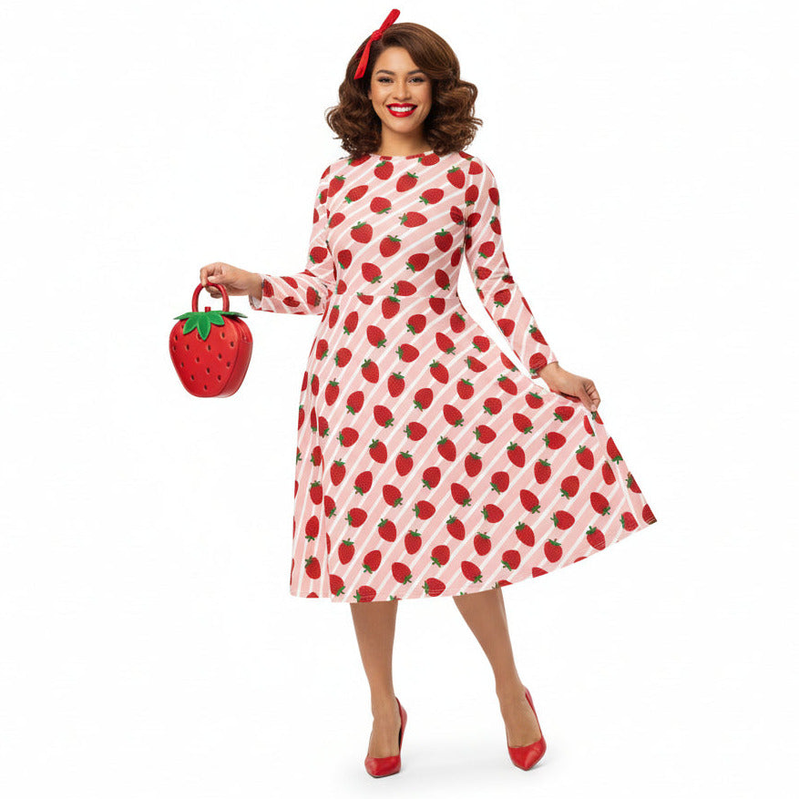 Woman wearing pink and red strawberry print longsleeve dress with pockets on white background
