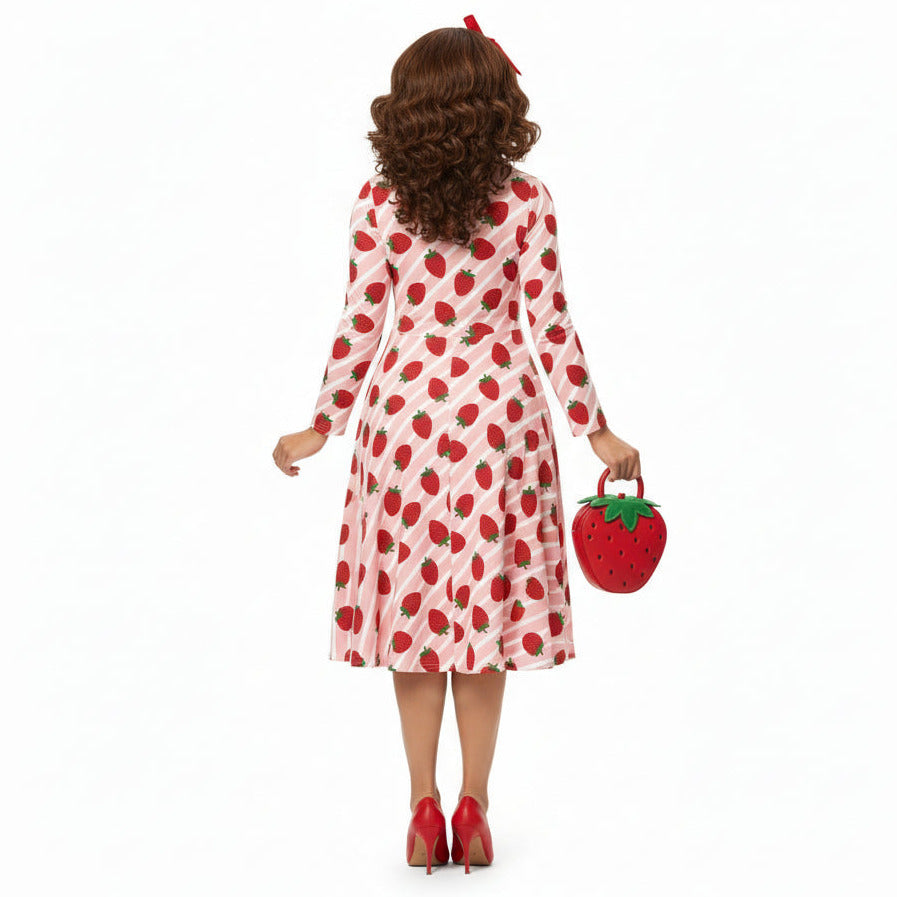 Woman wearing pink and red strawberry print longsleeve dress with pockets on white background