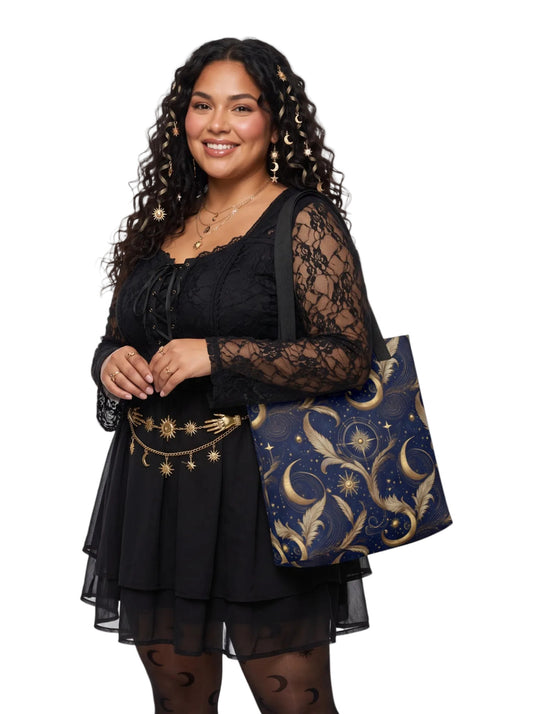 Woman wearing a whimsigoth sun and moon tote bag featuring feathers, moon and stars on a dark navy blue background.
