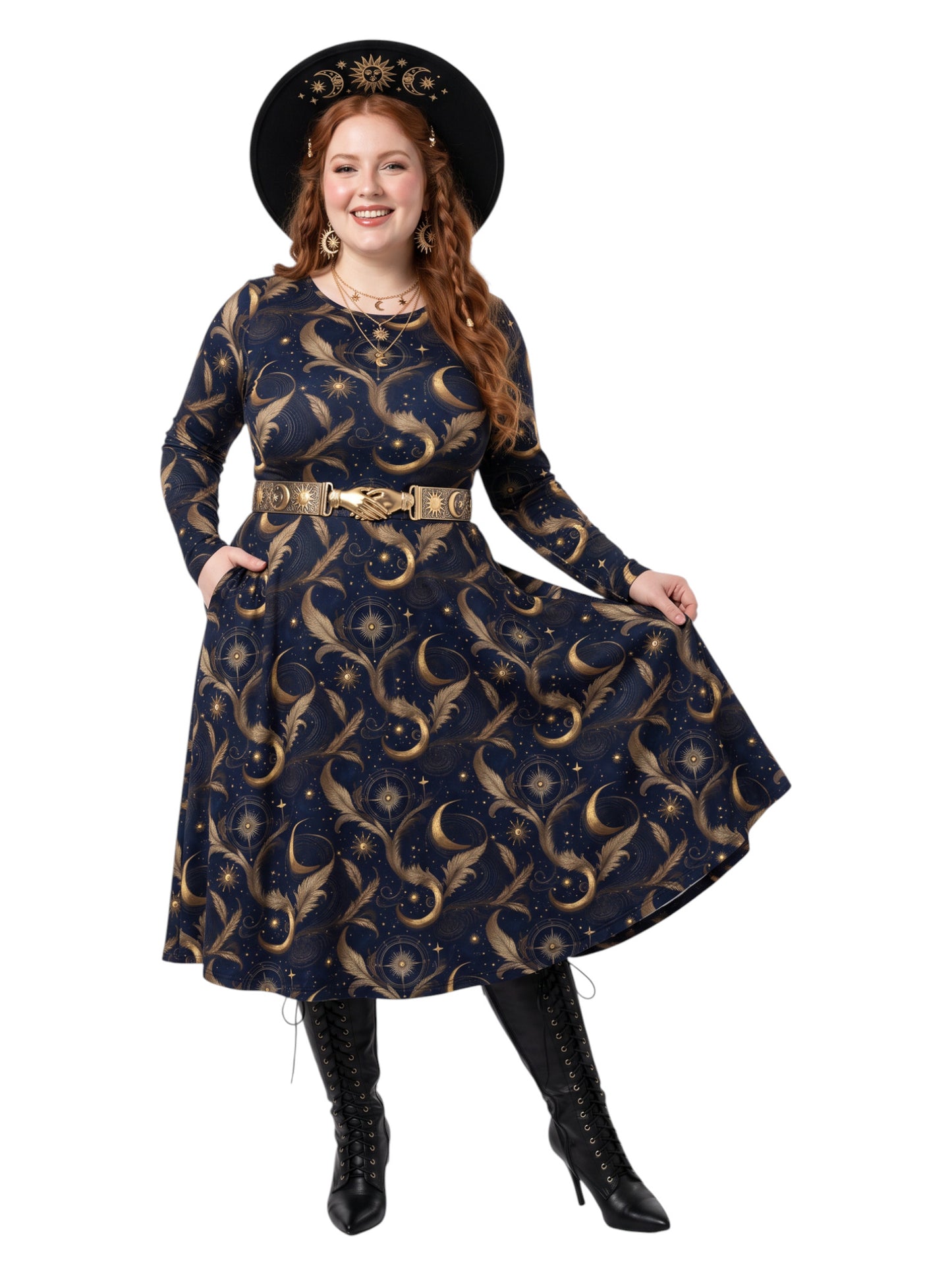 A woman modeling a long-sleeve navy blue dress with a gold celestial pattern of moons, stars, and leaves, styled with a matching belt, a black wide-brim hat, and black lace-up boots against a white background.