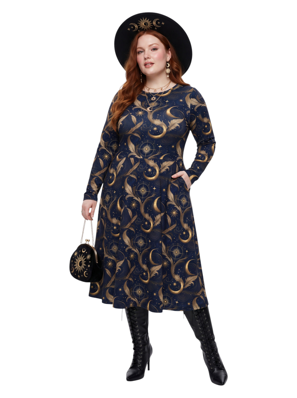 A woman modeling a long-sleeve midi dress with a celestial print in navy blue and gold, styled with a black wide-brim hat, a small black patterned handbag, and black heeled boots against a plain white background.