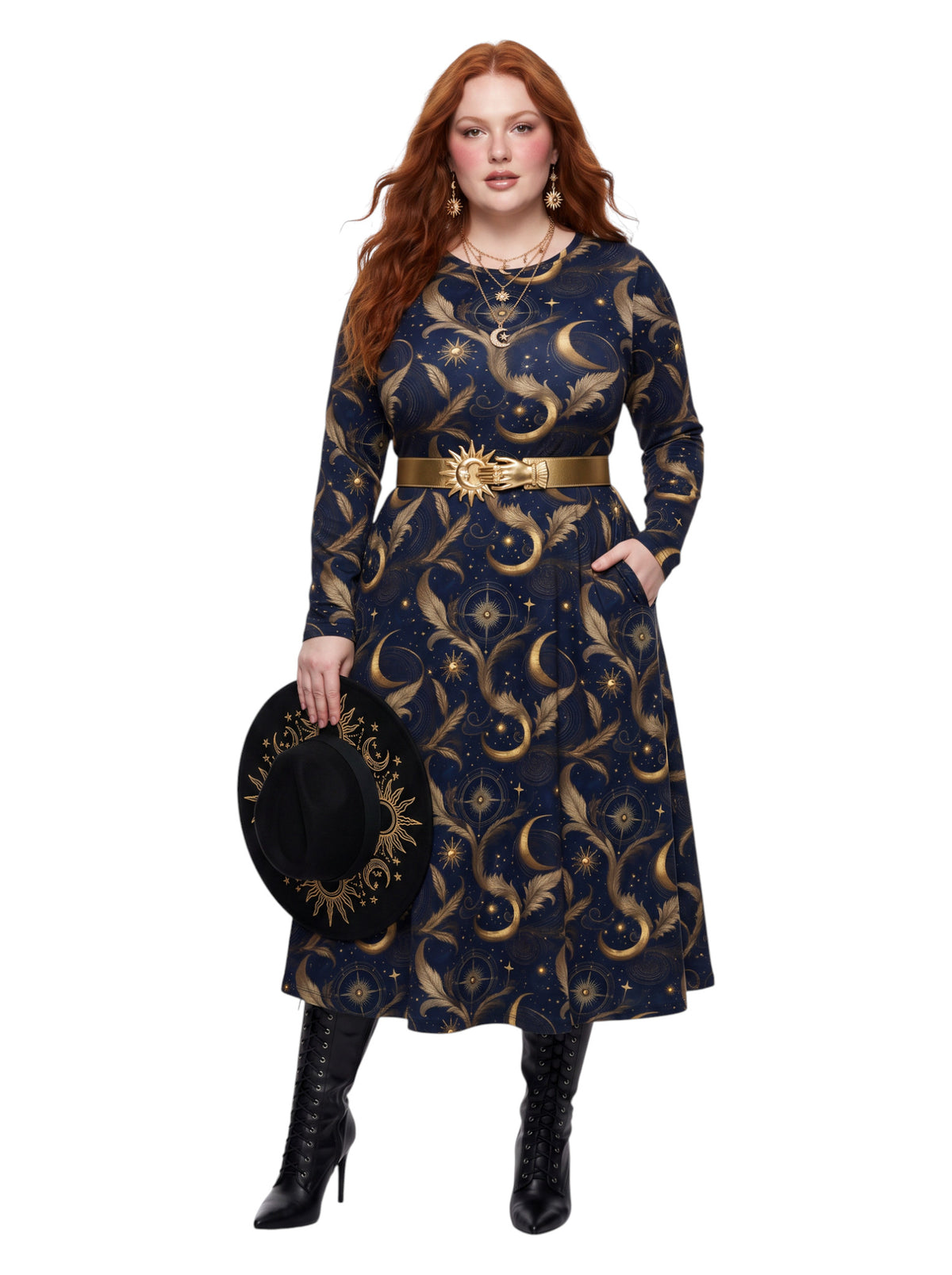 A woman modeling a long-sleeve midi dress with a celestial print of gold crescent moons and stars on a dark navy blue background. She is wearing a matching gold belt with a sun emblem and holding a black hat with a gold sun design, set against a plain white background.