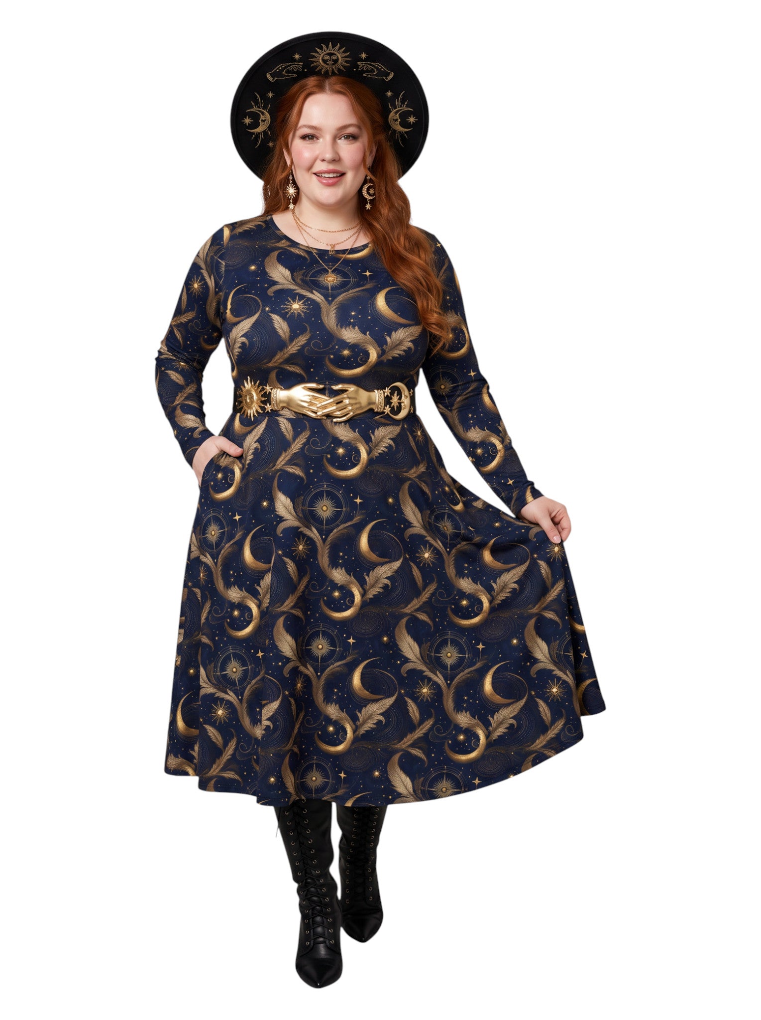 A woman modeling a long-sleeve navy blue dress with a gold celestial print of crescent moons, stars, and swirls, styled with a wide gold belt, a black witch hat, and black boots against a white background.