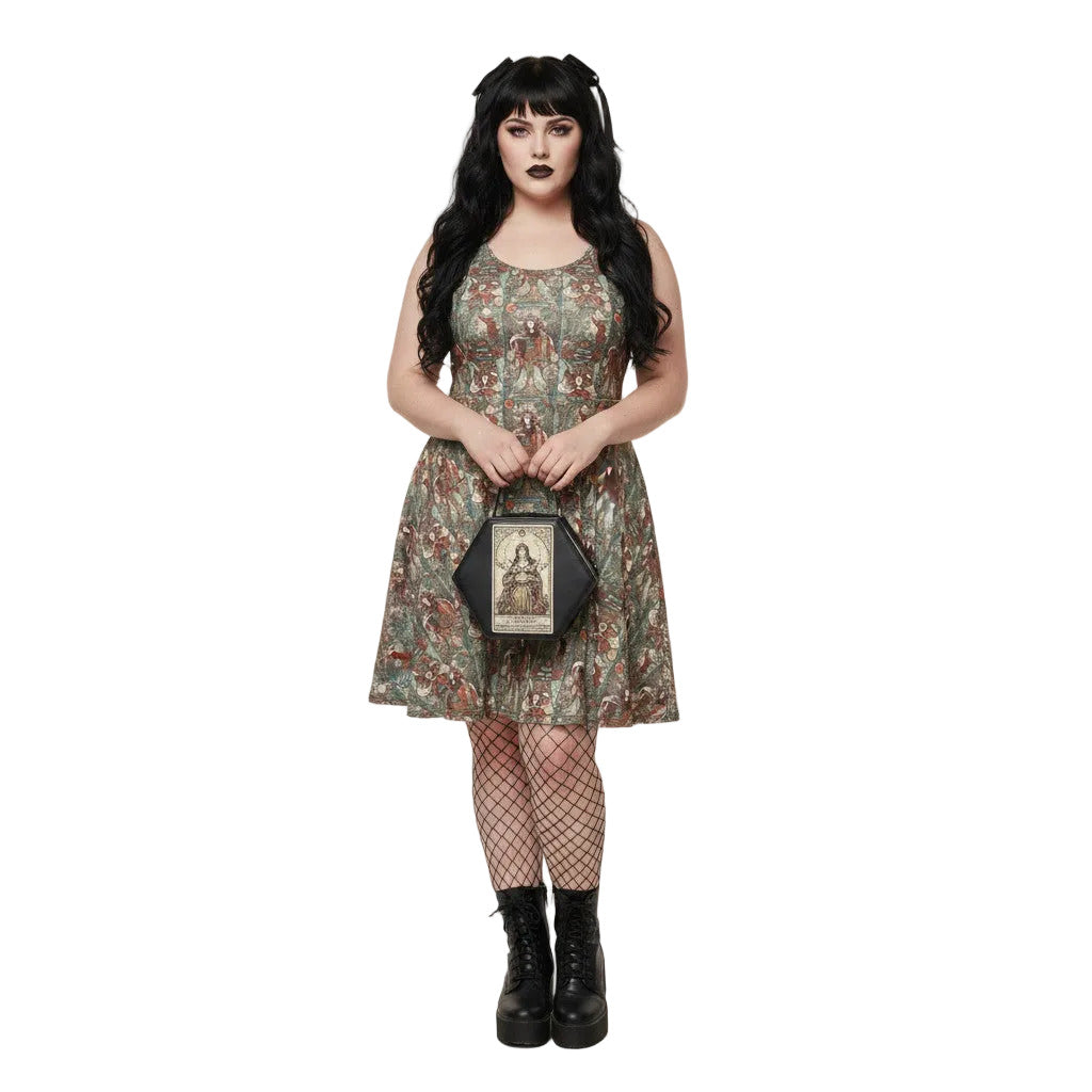 Woman wearing a green Whimsigoth tarot card print skater dress with black fishnets and a gothic handbag.