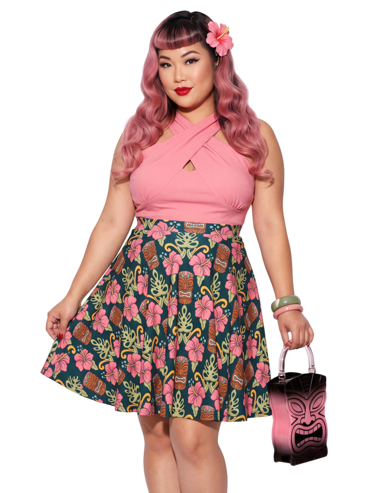 Plus-size woman wearing high-waisted tiki mask and hibiscus flower print pinup swing skirt with pink halter top.