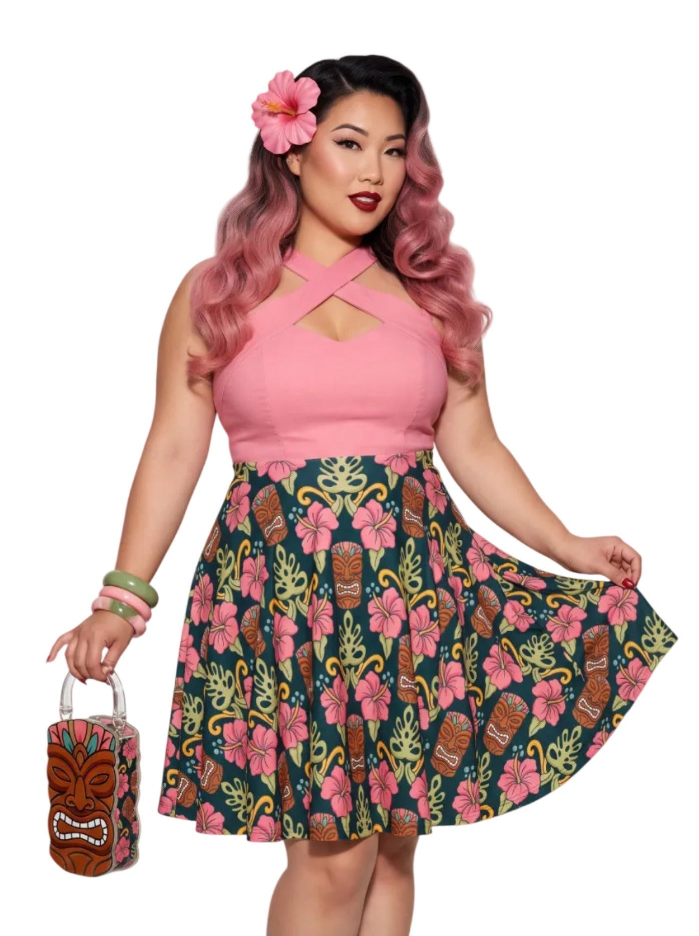 Plus-size woman wearing high-waisted tiki mask and hibiscus flower print pinup swing skirt with pink halter top.
