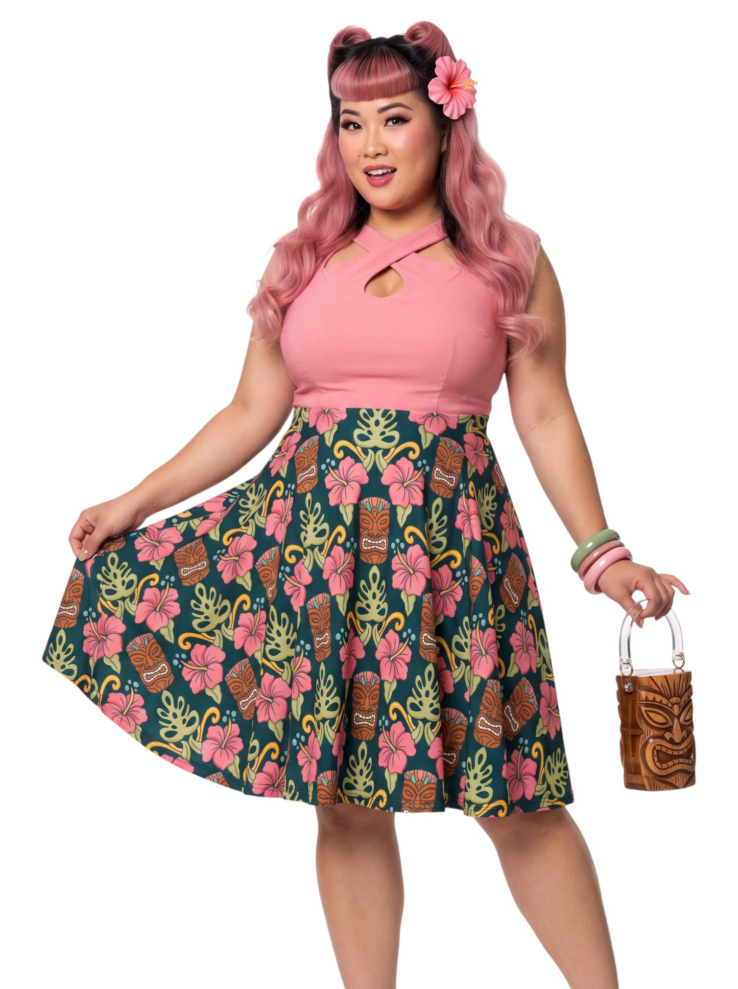 Plus-size woman wearing high-waisted tiki mask and hibiscus flower print pinup swing skirt with pink halter top.