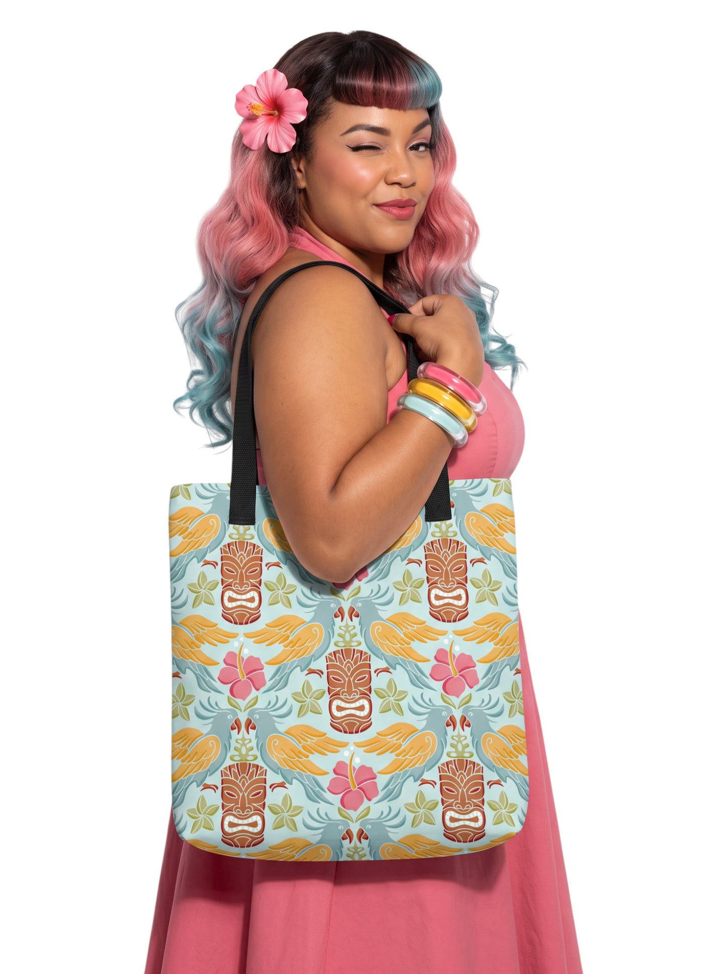 A woman holding a Tiki mask bird and hibiscus flower pattern tropical pinup tote bag with black handles.