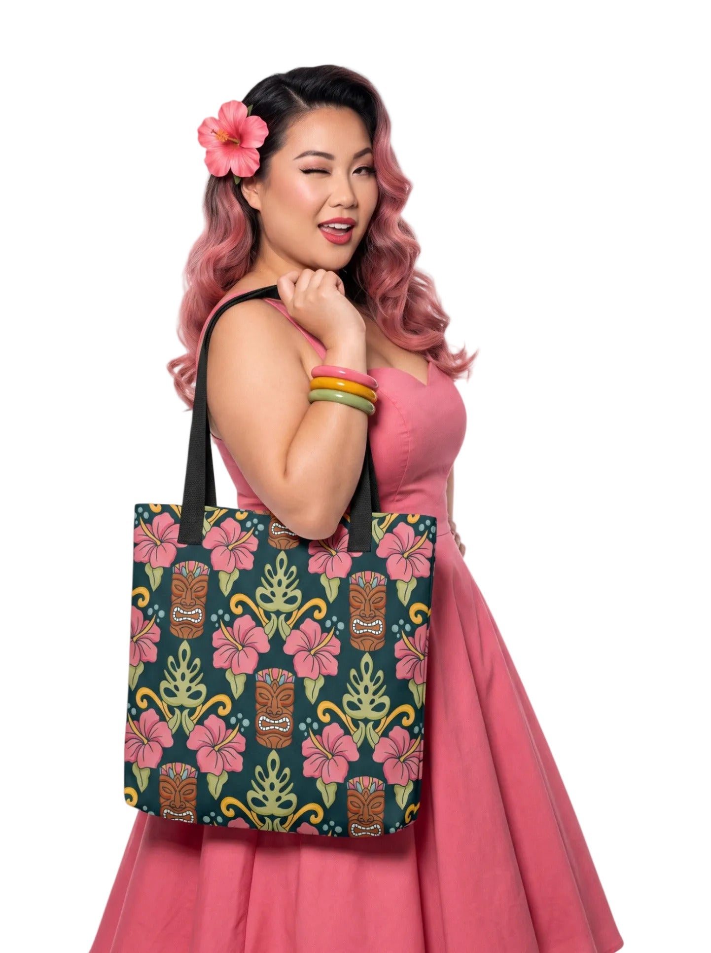 A woman holding a Tiki mask hibiscus flower pinup style tropical beach tote bag with black handles.