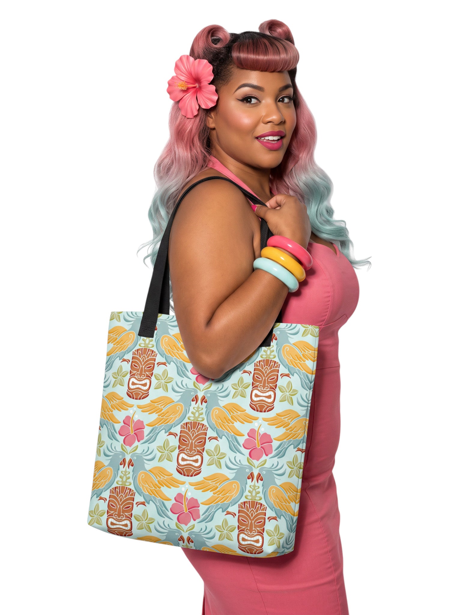 A woman holding a Tiki mask bird and hibiscus flower pattern tropical pinup tote bag with black handles.