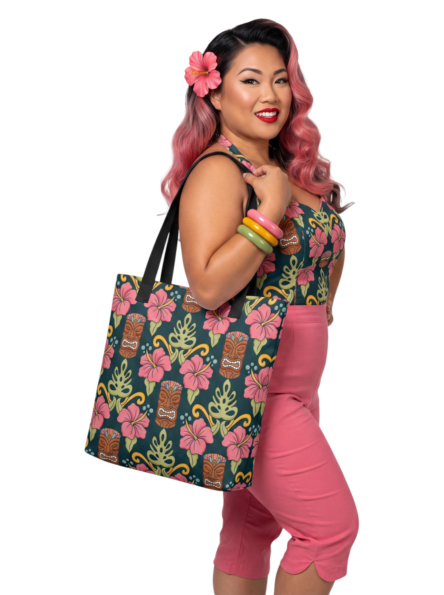 A woman holding a Tiki mask hibiscus flower pinup style tropical beach tote bag with black handles.