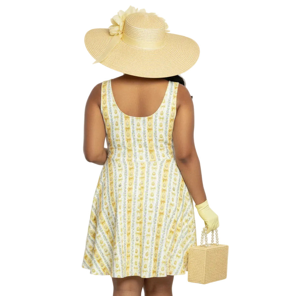 Plus size woman wearing a yellow 1950s vintage-inspired fit and flare dress with an Easter egg pattern, styled with a straw hat and pearls.