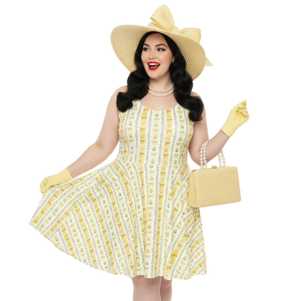 Plus size woman wearing a yellow 1950s vintage-inspired fit and flare dress with an Easter egg pattern, styled with a straw hat and pearls.